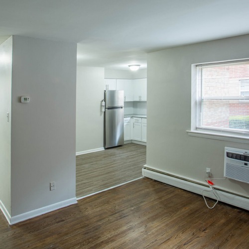 Spacious and well lit living room with wood floors and an open floor plan with access to the kitchen.