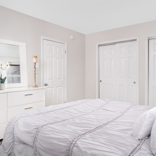 Spacious and well lit bedroom with plush carpet and large windows