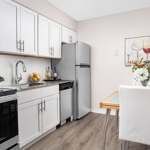 Spacious and well lit kitchen with wood floors and stainless steel appliances. 